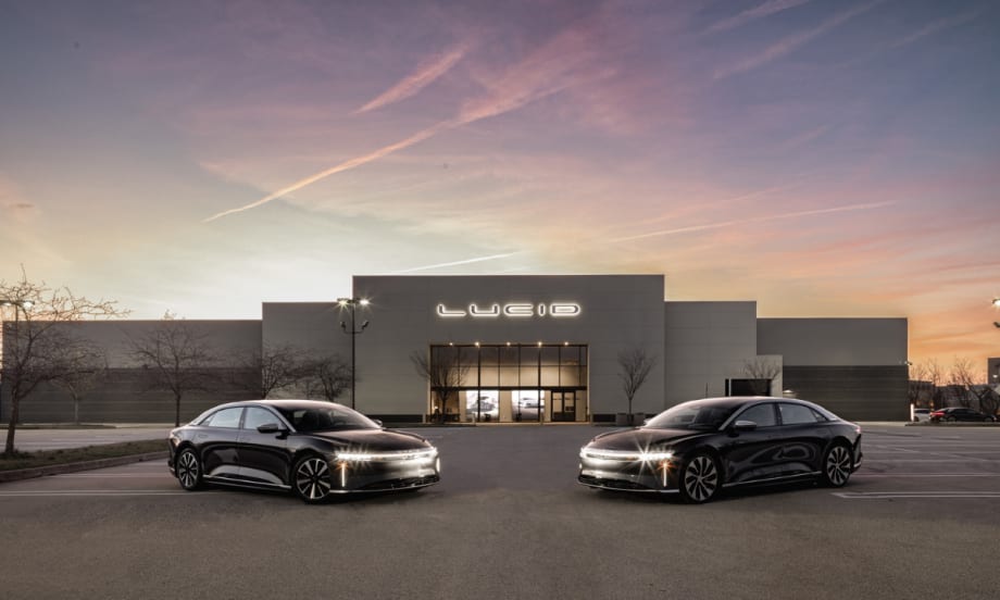 Two Lucid electric sedans parked in front of a Lucid facility at dusk, representing the automaker’s new certified pre-owned vehicle program.