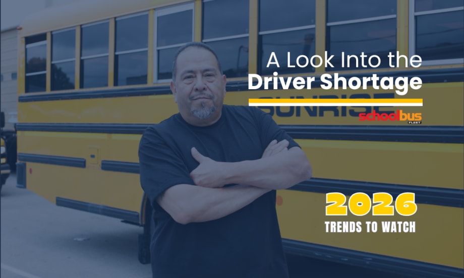 School bus driver stands with arms crossed in front of a yellow Sunrise school bus, with text reading “A Look Into the Driver Shortage” and “2026 Trends to Watch” from School Bus Fleet.