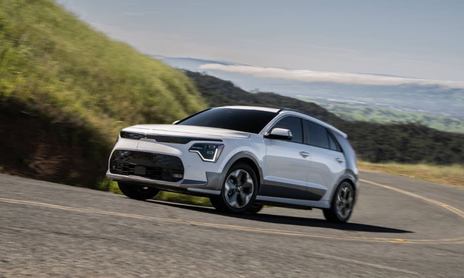 2026 Kia Niro EV driving on a winding road through a hilly landscape.