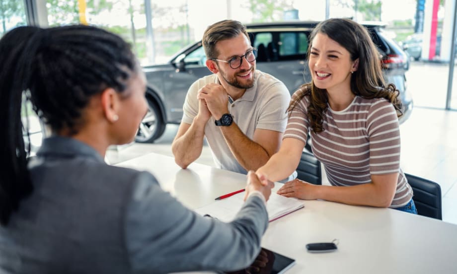 A dealership customer works with an F&I representative at a desk during the vehicle purchase process.
