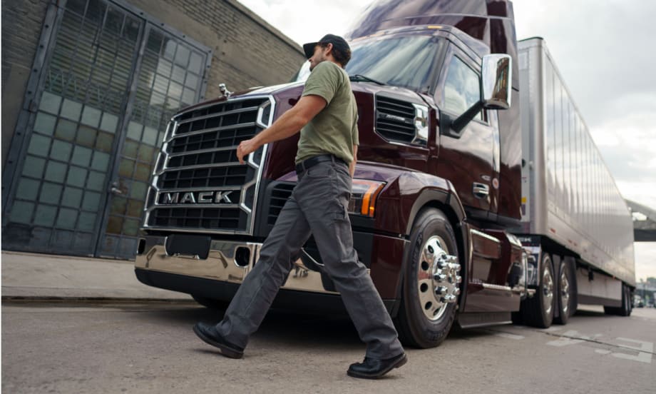 Man walks across in front of a Mack tractor trailer.
