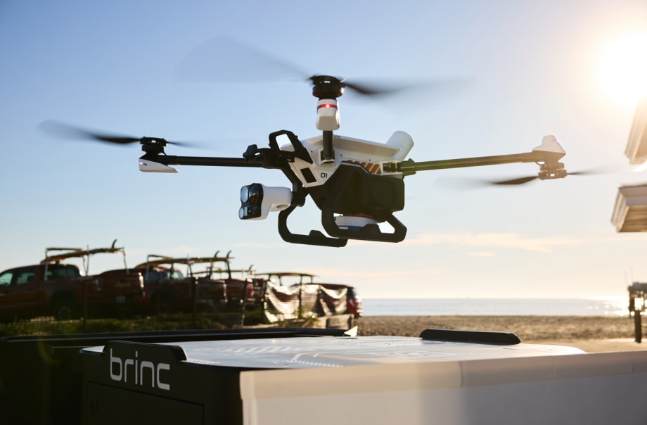 Police drone hovering over its charging nest against a blue sky background.