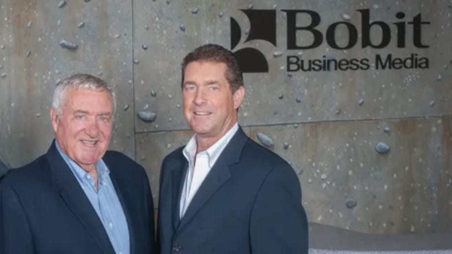 Ed Bobit and his son Ty Bobit standing together in front of Bobit Business Media sign, representing leadership and legacy in the fleet industry.