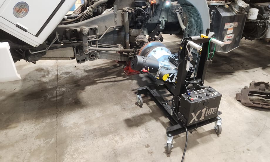 A brake lathe is attached to a truck wheel in a repair shop.