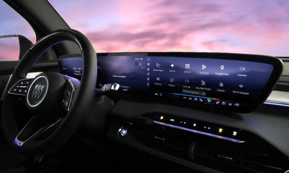 View of a GM vehicle dash with a large infotainment screen and purple sky viewed through windshield.