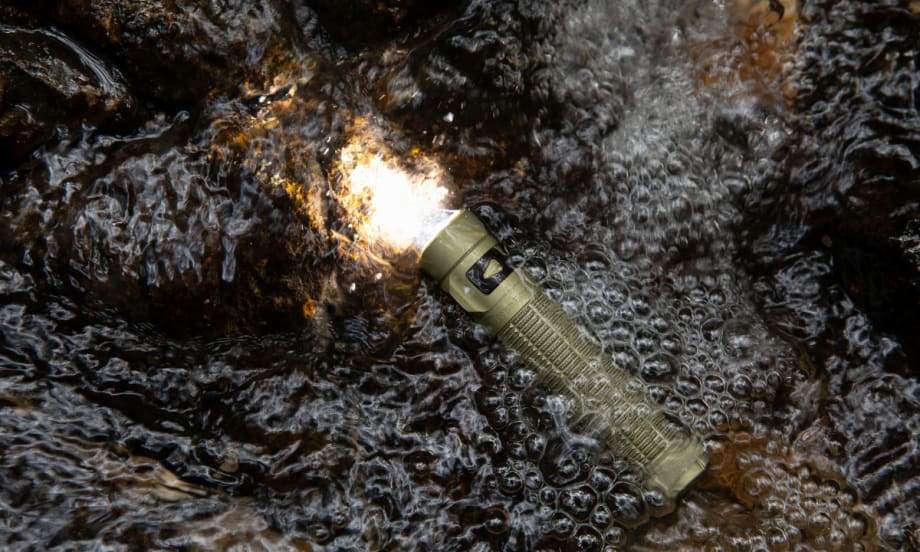 flashlight turn un and submerged in puddle with rain falling.