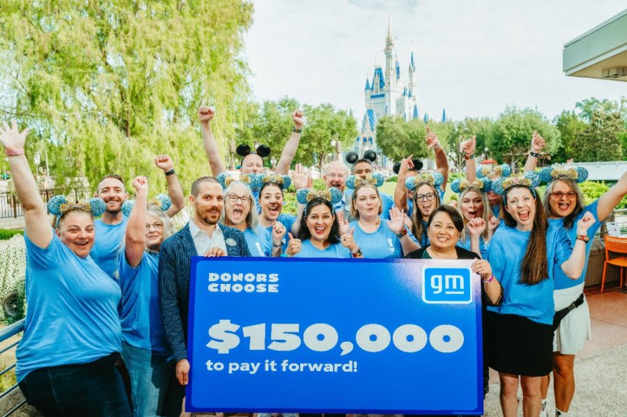 Adults in blue shirts holding  a banner with headline $150,000 with Disney World castle in the background.
