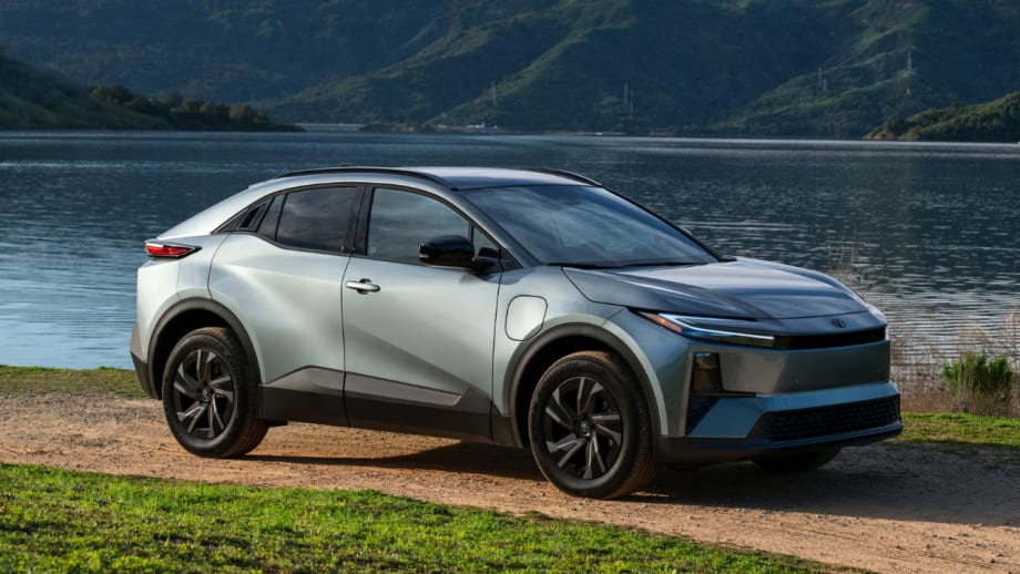 Silver 2027 Toyota C-HR battery-electric SUV parked beside a lake with mountains in the background.
