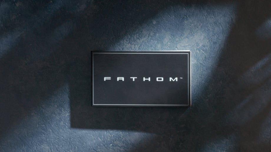 Black Fathom nameplate mounted on a dark textured wall, illuminated by soft directional lighting that creates subtle highlights and shadows, emphasizing the brand’s minimalist, modern aesthetic.