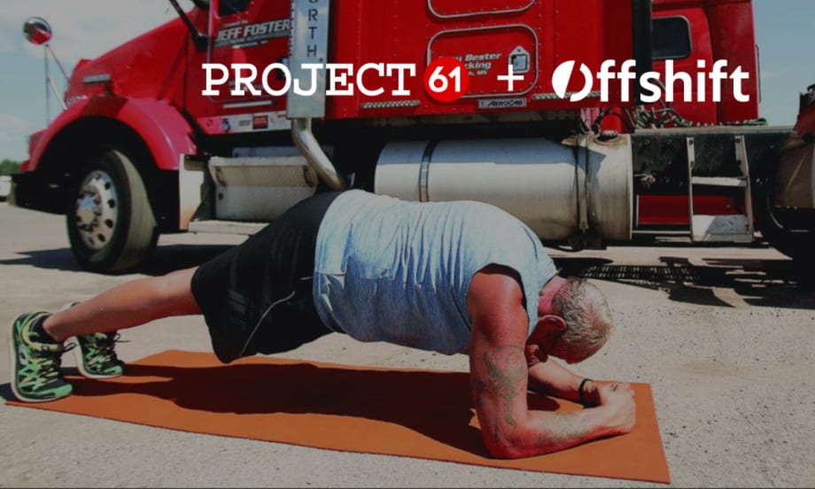 Truck driver doing a plank exercise on a mat with a red truck in the background.