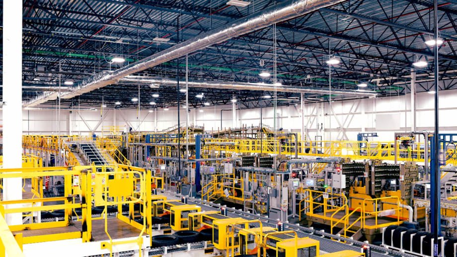 Wide view of yellow manufacturing equipment, conveyors, platforms, and overhead infrastructure inside Ford’s Louisville Assembly Plant.