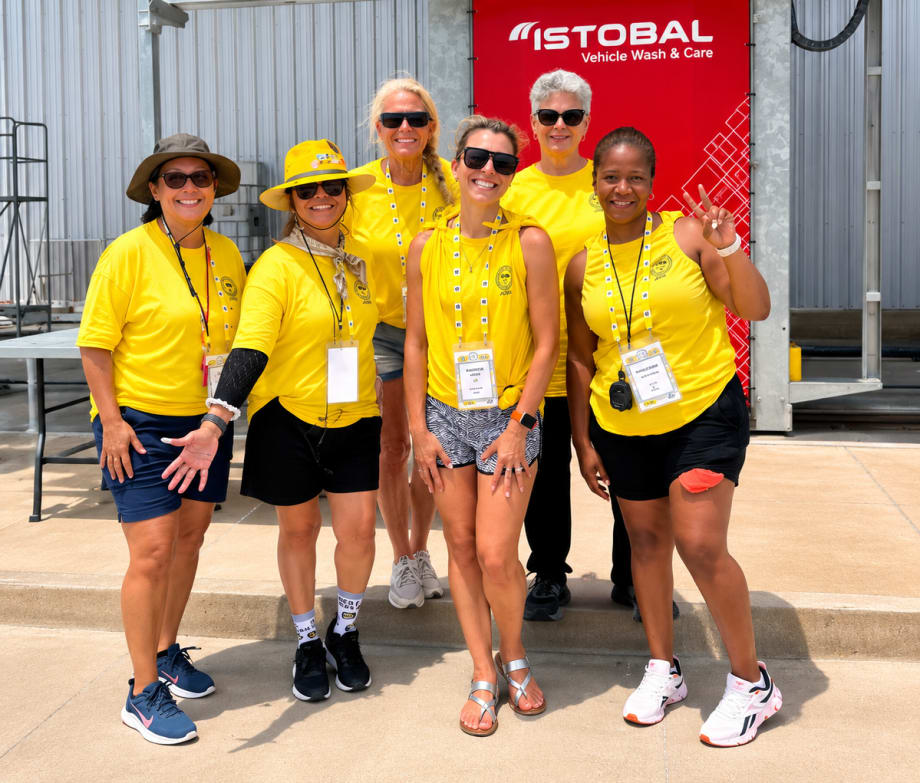 Six people stand next to each other in yellow shirts at the school bus driver competition