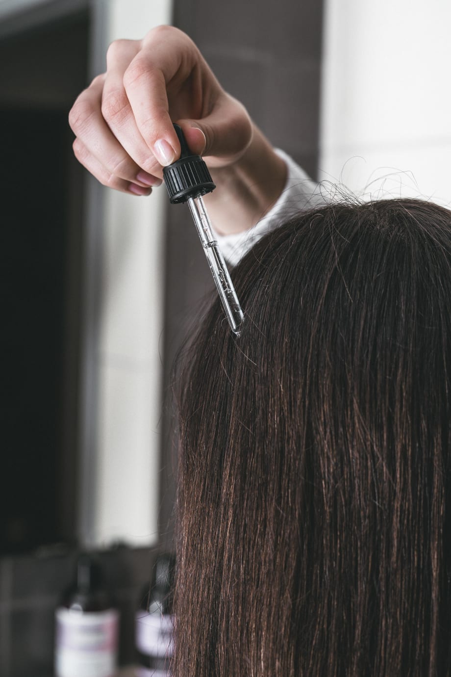 the rear view of a head of hair, having serum dropped onto the scalp.