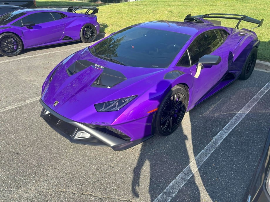Vibrant purple Lamborghini sports car with aerodynamic design parked on asphalt