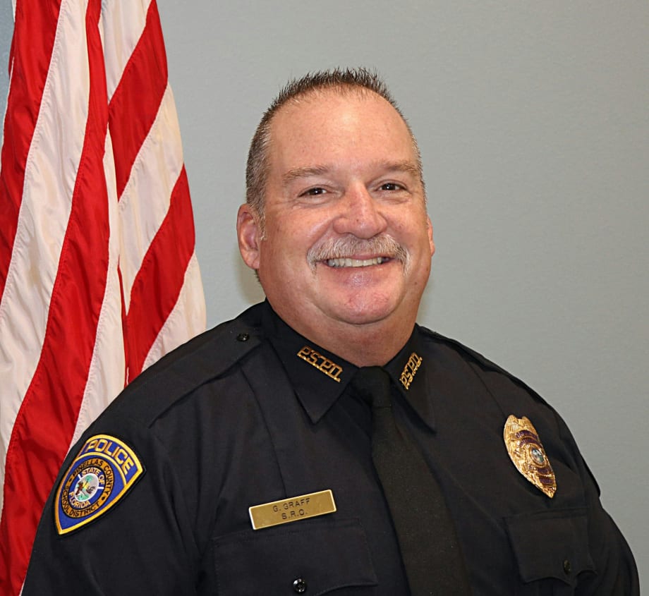 Smiling police officer in black uniform standing in front of American flag