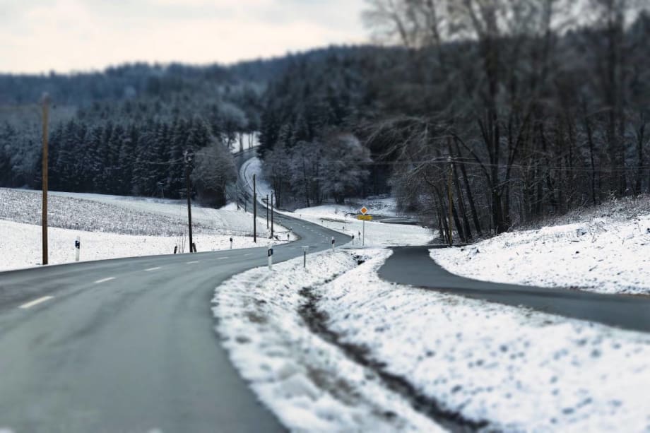 A long snowy road goes uophill.