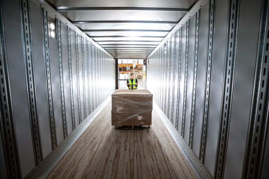 Empty trailer with worker loading a pallet of cargo