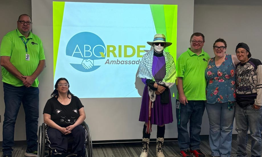 ABQ RIDE Transit Ambassadors pose in front of a projector screen.
