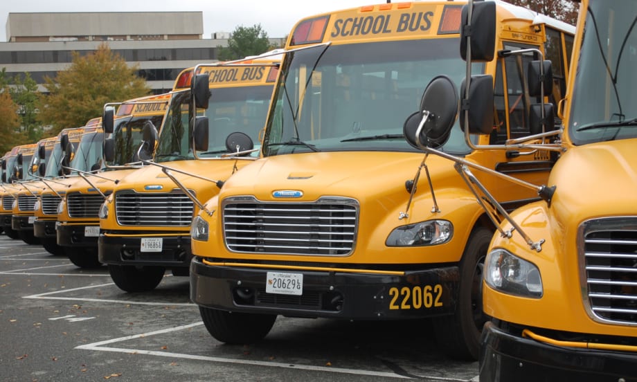Electric school buses parked in a parking lot.