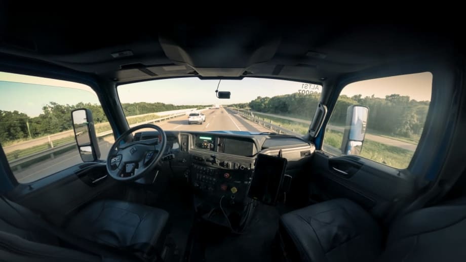 Interior of Class 8 truck cab, with no one in driver or passenger seats, looking out front and side windows from sleeper in a wide angle shot.