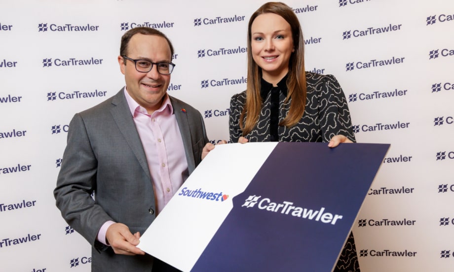 Two execs hold up a sign with Southwest and CarTrawler logos