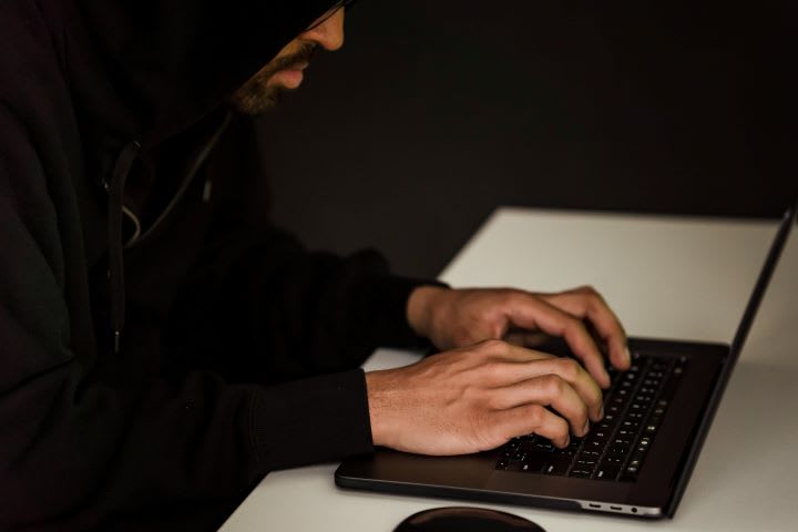 Photo of man with most of his face hidden as he types on a computer keyboard