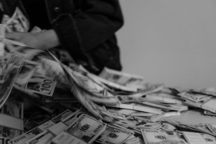 Photo of person grabbing stacks of cash from a surface