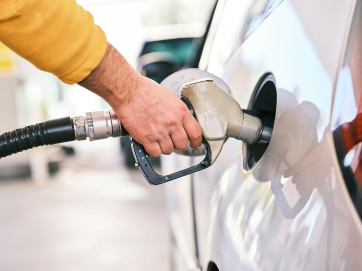 Man's hand holding gas pump in fuel tank of white car