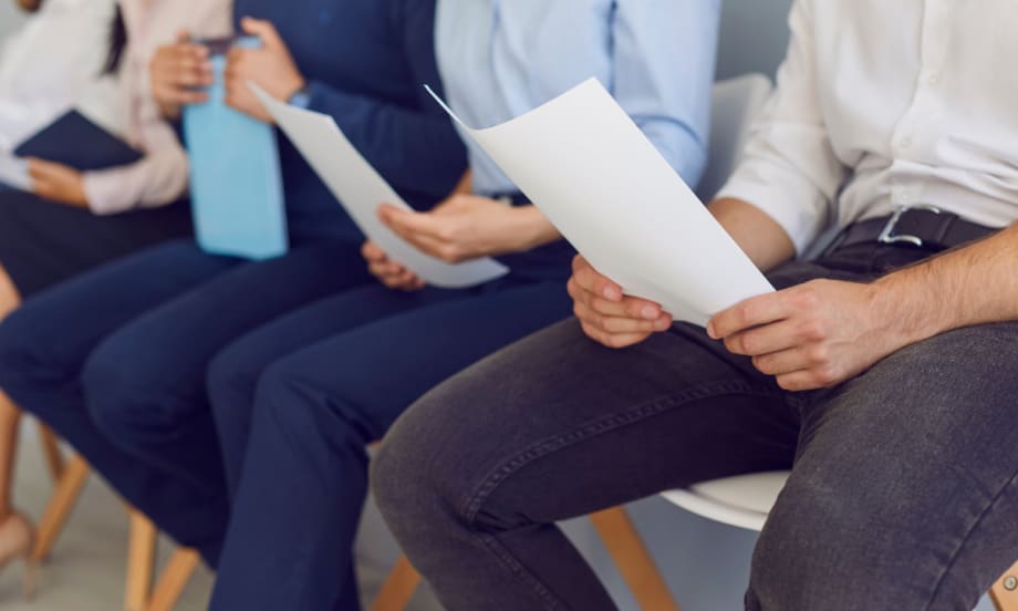 a line of people sitting down with paperwork in their hands