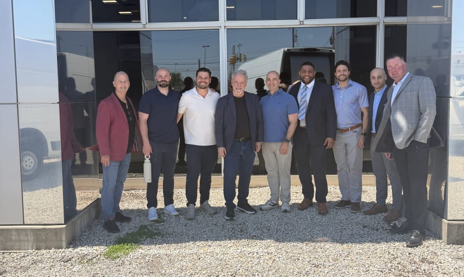 Group photo of men outside storefront.