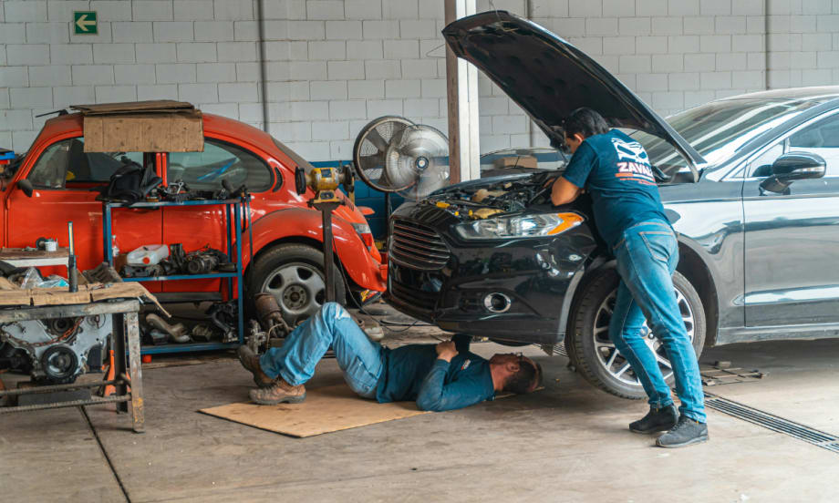 Two men do mechanical work on car.