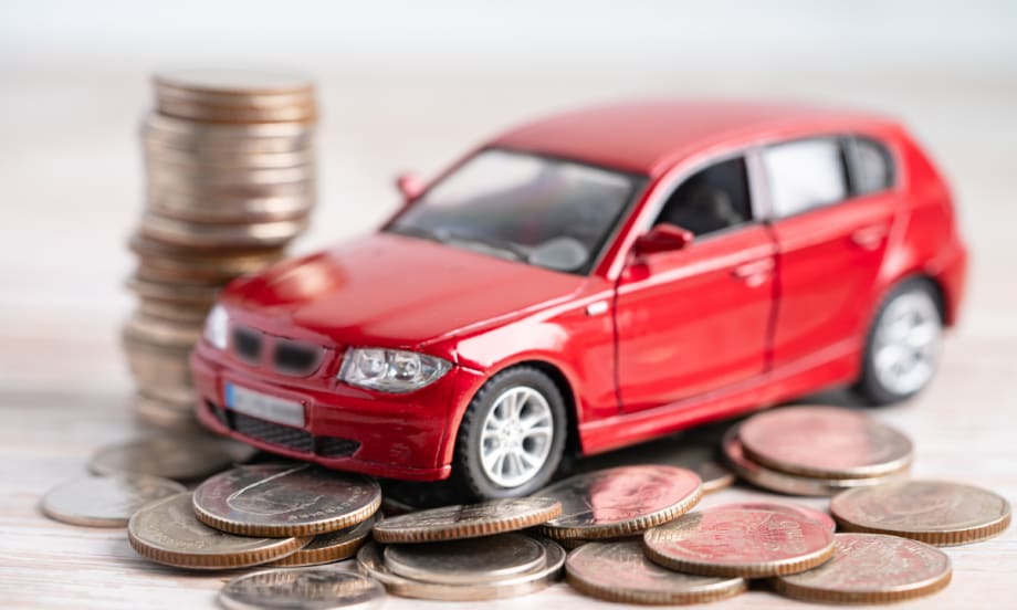Red toy car sitting on top of coins.