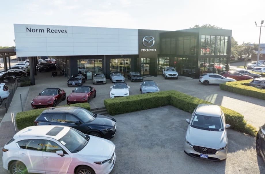 Photo of the exterior of a recently purchased Mazda car dealership with cars for sale parked in front