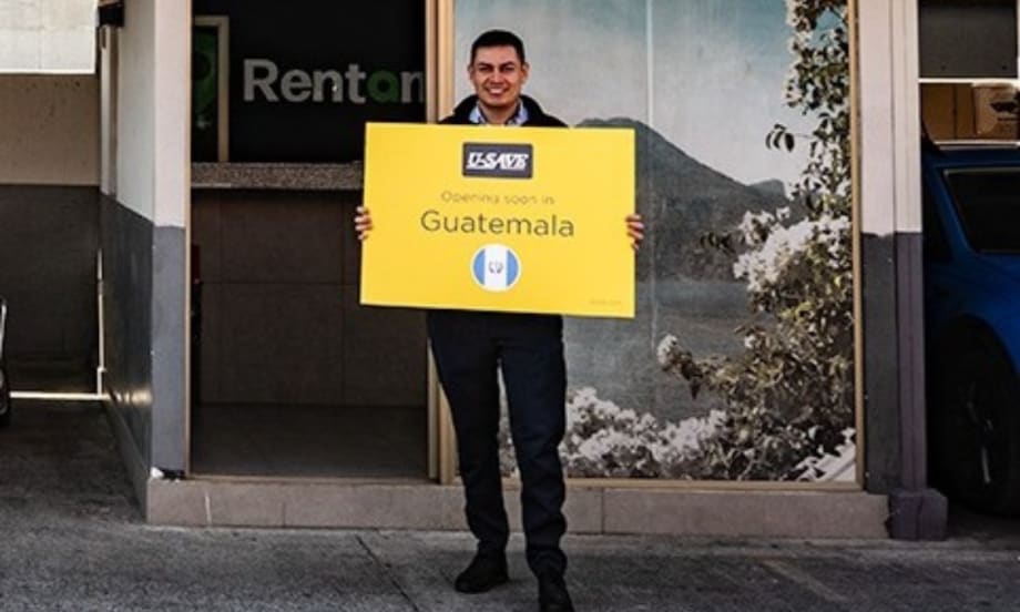 Franchisee standing with yellow U-Save branded sign in front of the rental car outlet.
