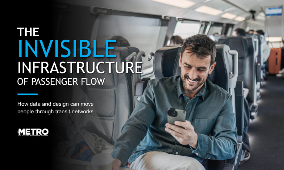 A man sits in a passenger rail seat and looks at his phone.