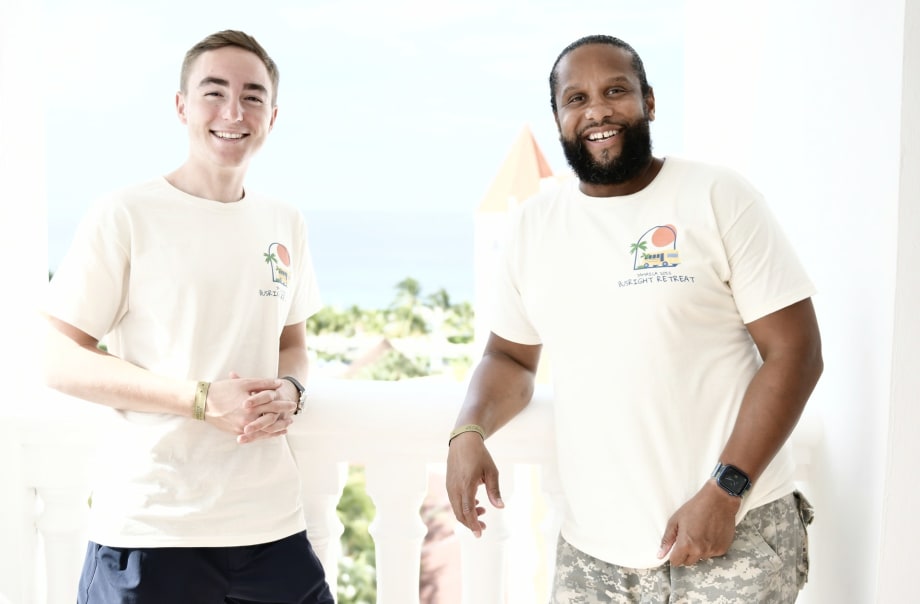two men stand next to each other in white t-shirts
