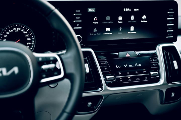 Phot of a dark Kia vehicle interior with steering part of steering wheel and dashboard