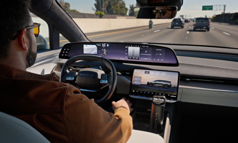 Man behind a steering wheel driving hands-free in a Lucid Gravity on the freeway.