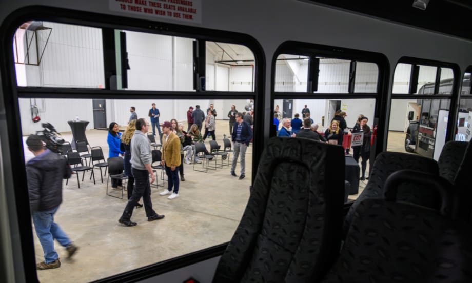 Perspective through the window of a transit bus into a warehouse event space for Arrowhead Transit.