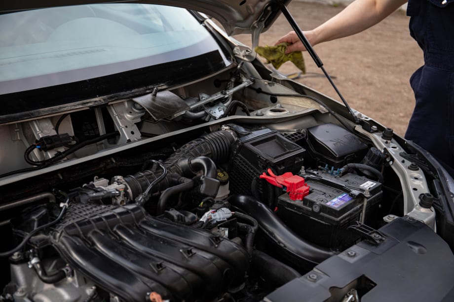Arm of mechanice reaching for car with hood open