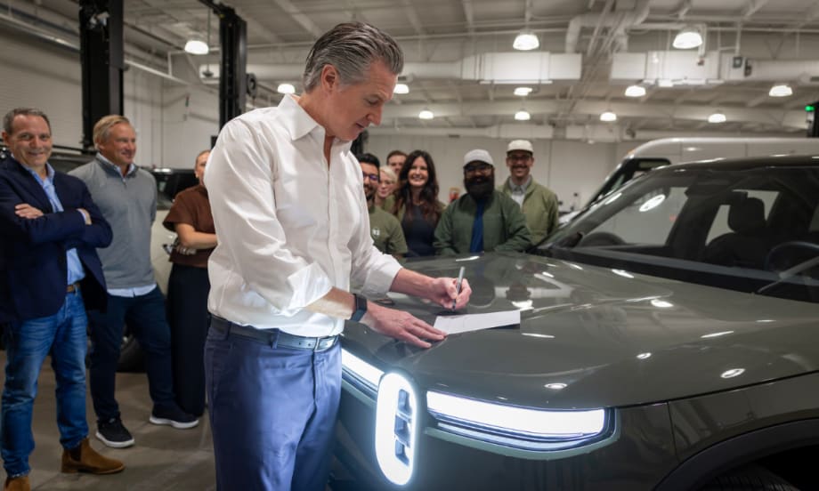 Gov. Newsom signs legislation on the hood of an EV.