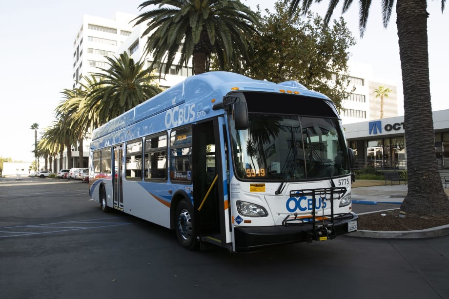 A blue and white OCTA public transit bus parked in the street.