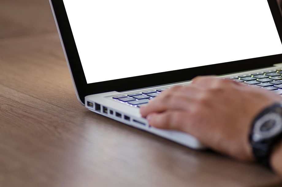 Photo of man's hand on laptop computer keyboard with blank screen