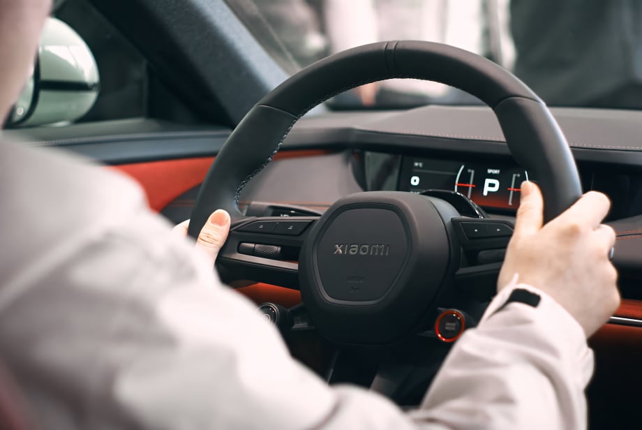 inside of car, person with hands on black steering wheel