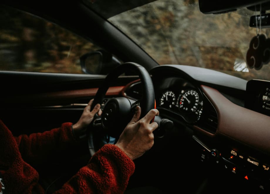 inside of car, view of steering wheel with hands on it driving