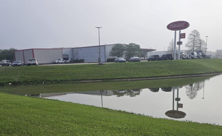 Photo of truck dealership with pond in foreground