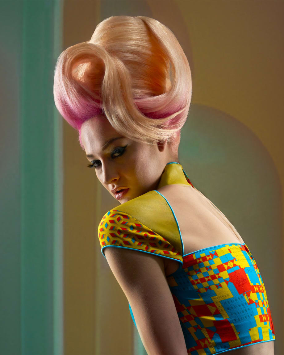 A model with a pink bouffant hairstyle in a multicolored shirt