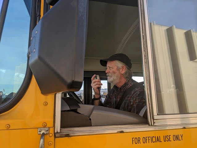a man drives a school bus and talks through the radio