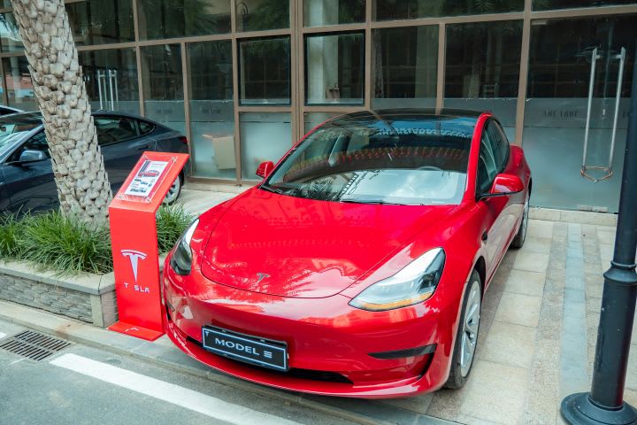 Photo of red Tesla car parked outside of building