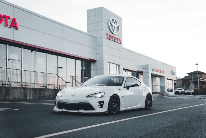 Photo of white Toyota car in front of dealership